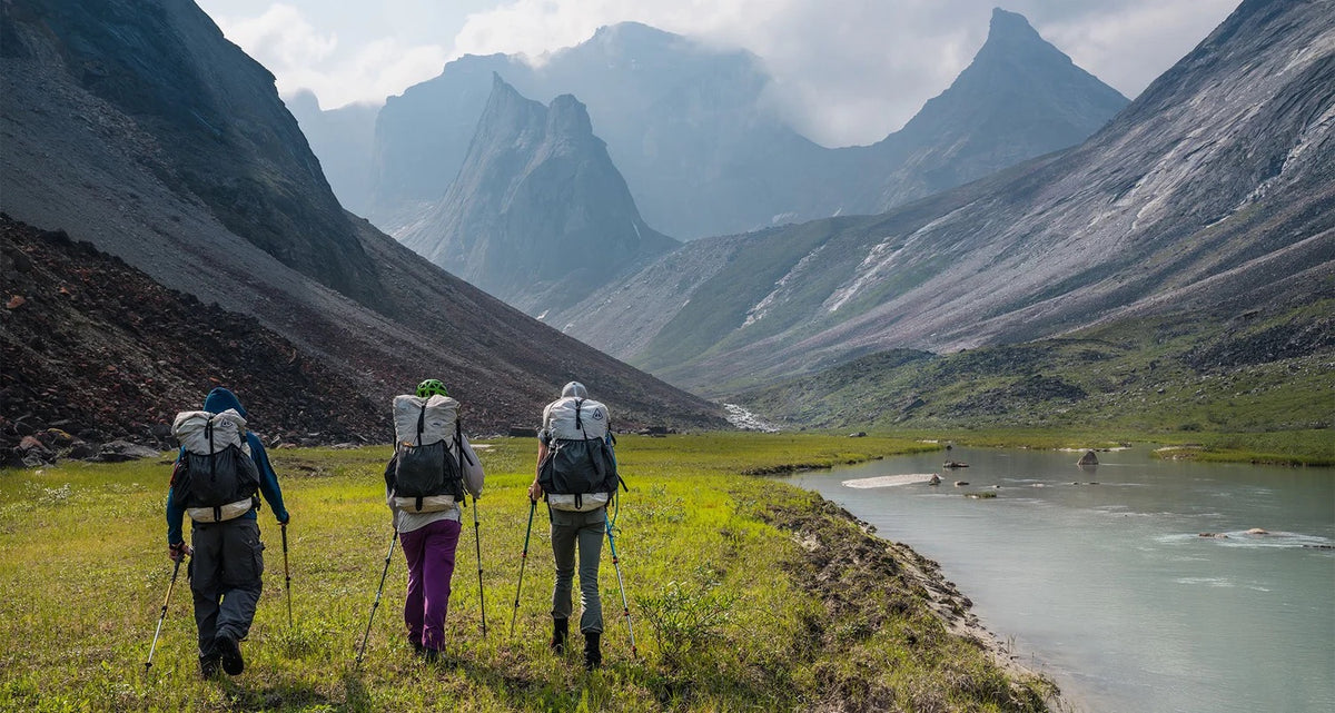 three backpackers with Hyperlite packs near a mountain lake