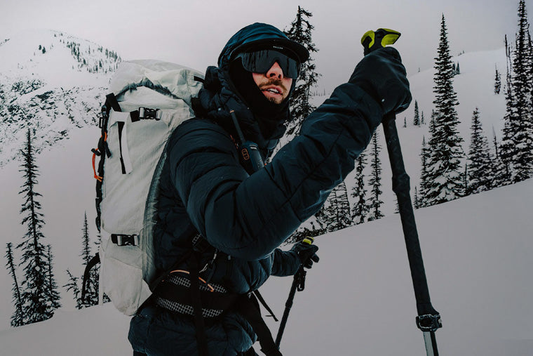 Person hiking in a snowy landscape with backpack and ski poles