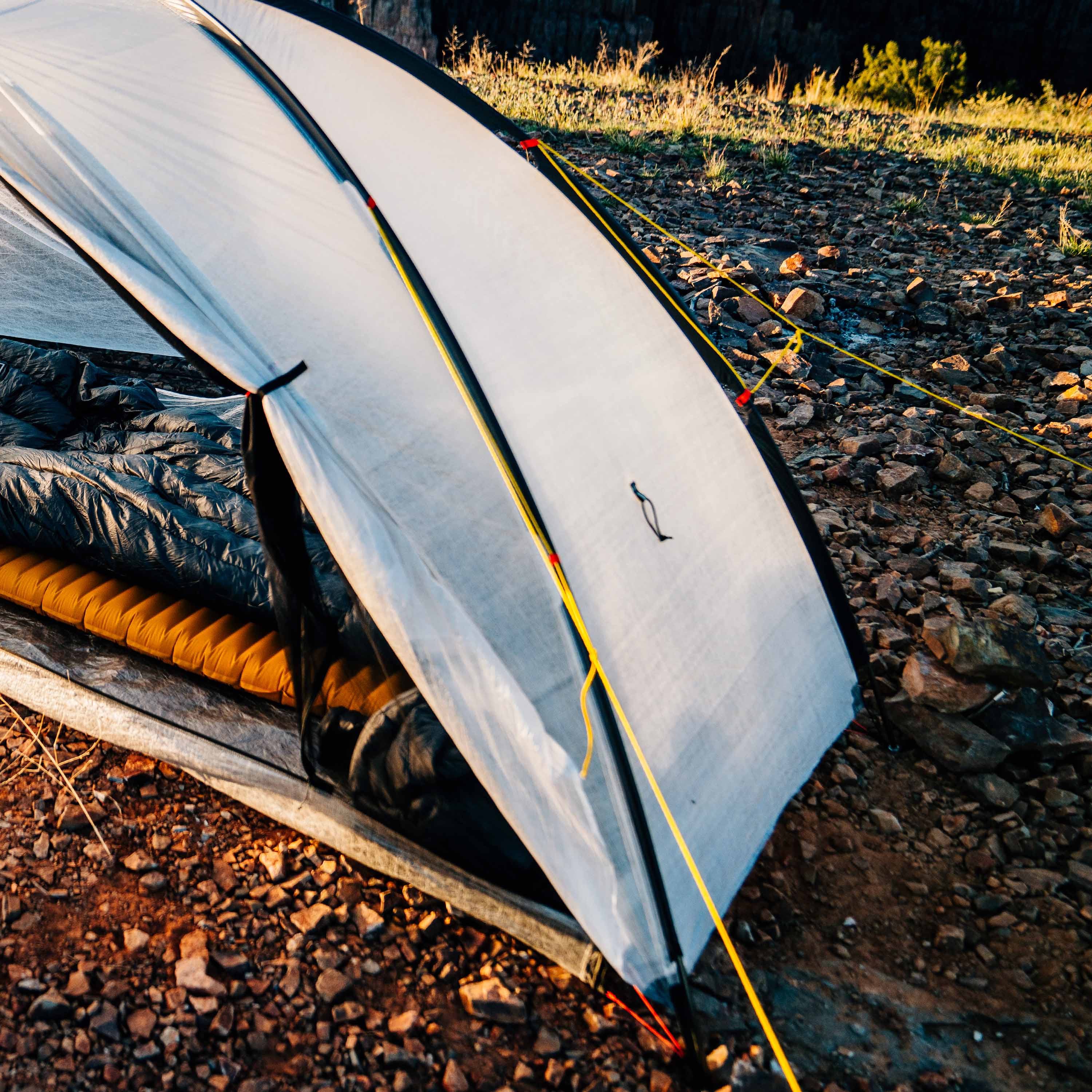 Camping tent set up on a rocky terrain with a natural outdoor setting.