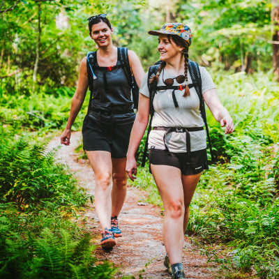 Two people hiking on a trail in a forest