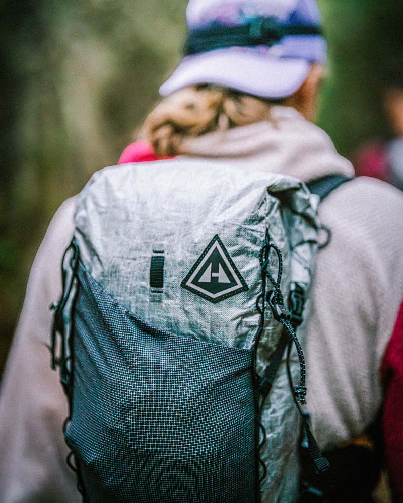Person wearing a grey Pemi 15 Hyperlite Mountain Gear backpack, standing outdoors.