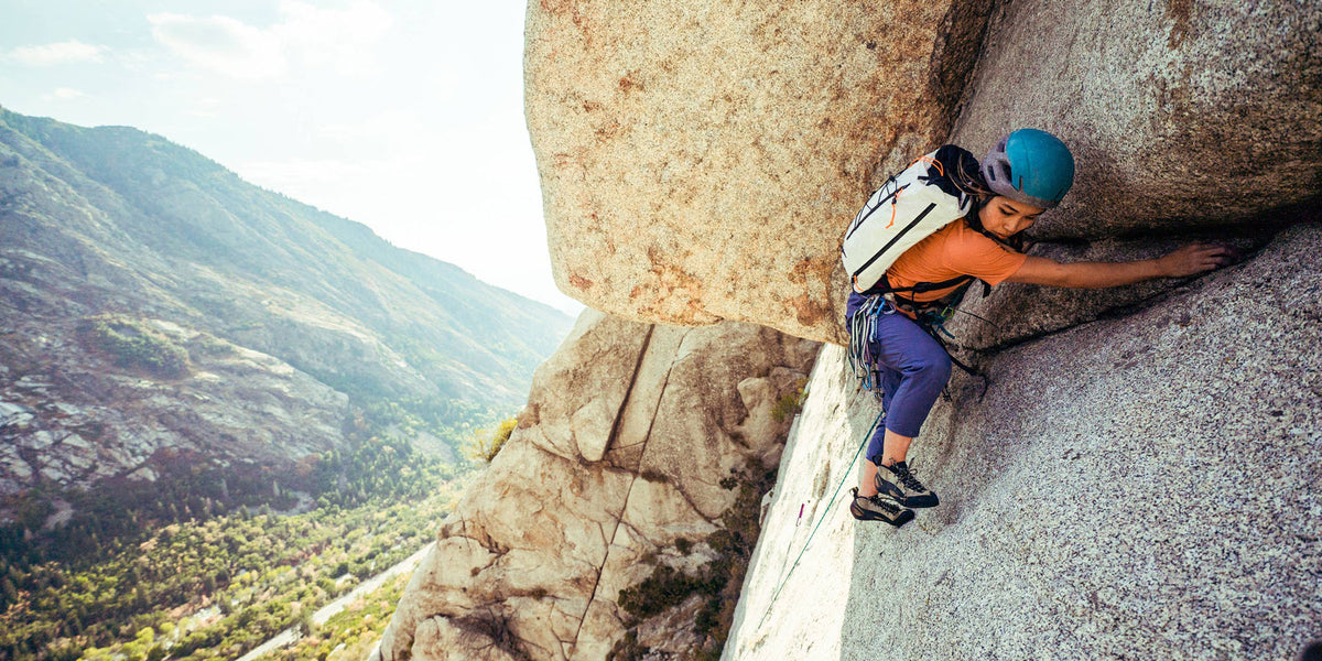 Person climbing a rocky mountain with a Hyperlite Mountain Gear Vertex 32 backpack.